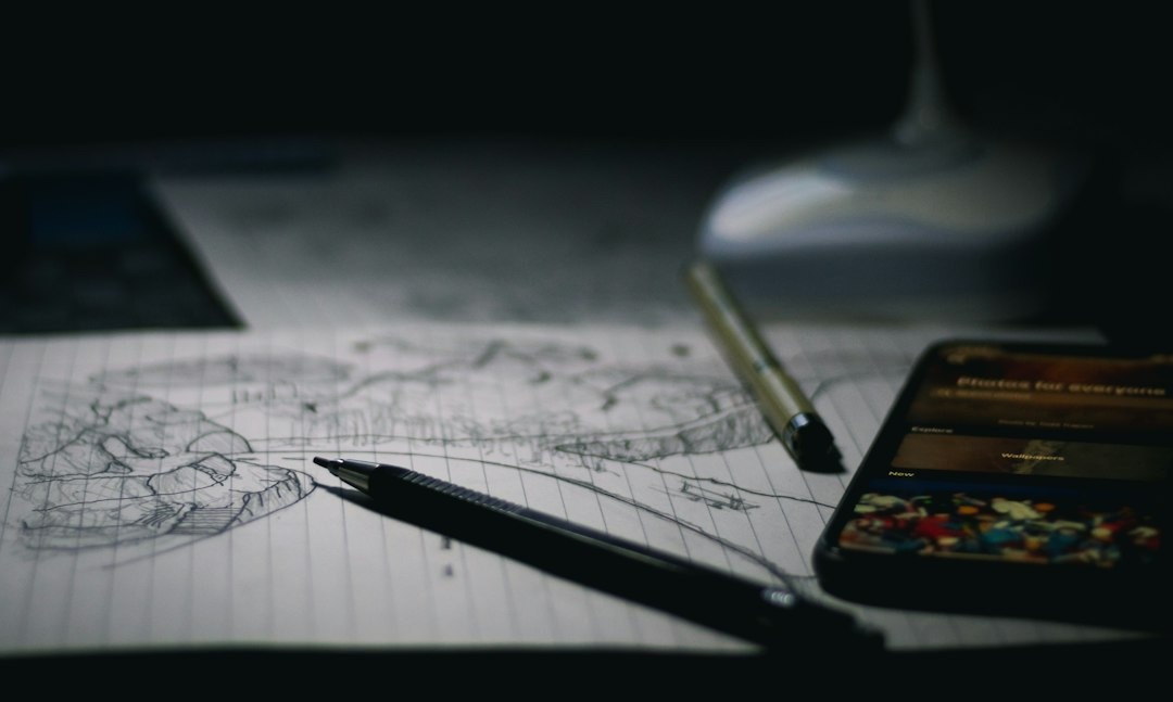 A mechanical pencil and gold pen rest on a landscape sketch.